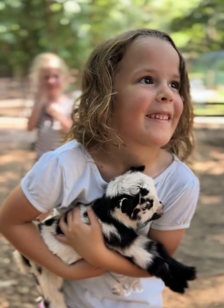 A smiling child holding a black and white baby rabbit